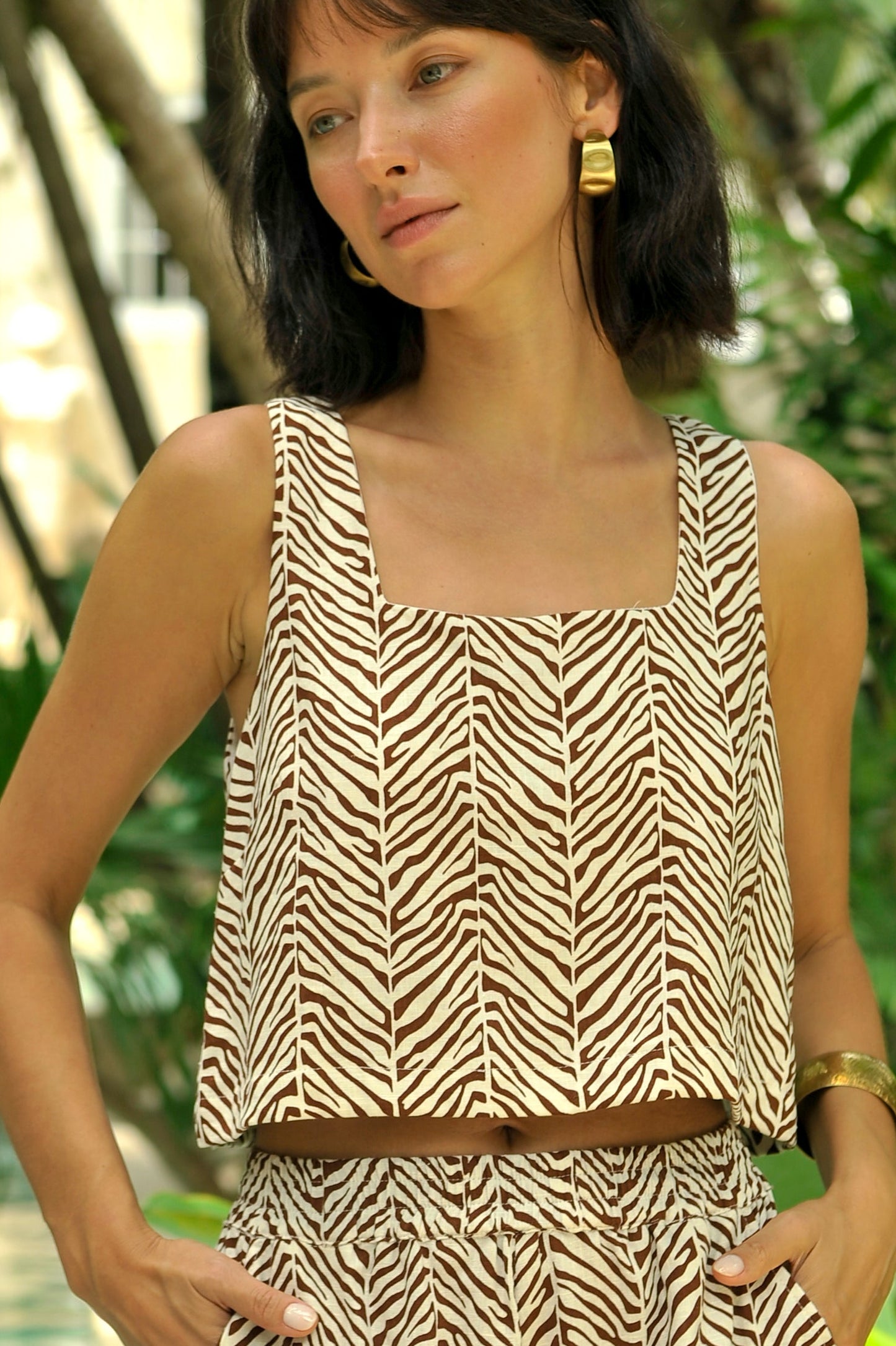 Woman wearing a zebra print outfit standing by a pool with greenery in the background