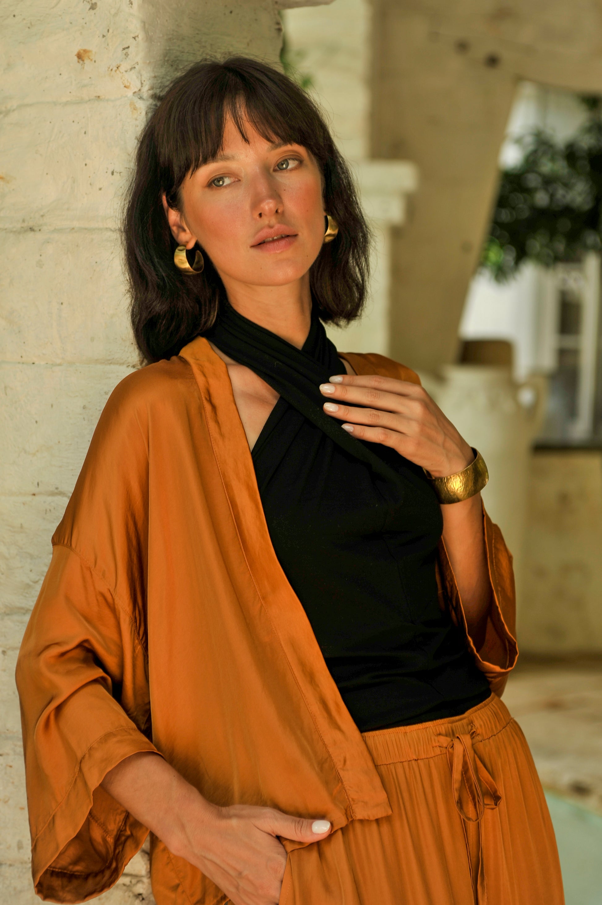 Woman wearing a mustard jacket and black top with a blurred background