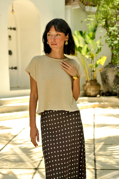 Woman wearing a beige top and polka dot skirt outdoors