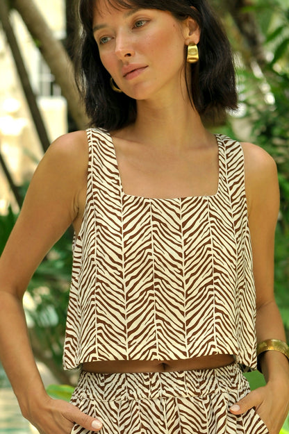 Woman wearing a zebra print outfit standing by a pool with greenery in the background